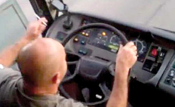 Șoferul scoate țigara pe geam după ce trage câte un fum
