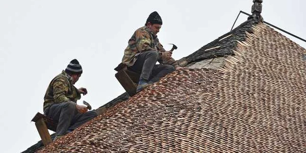 Doi meşteri în lemn fixează şindrila de pe acoperişul tradiţional al Hanului lui Manuc din Piaţa Unirii din Bucureşti FOTO Mediafax / Marian Ilie 