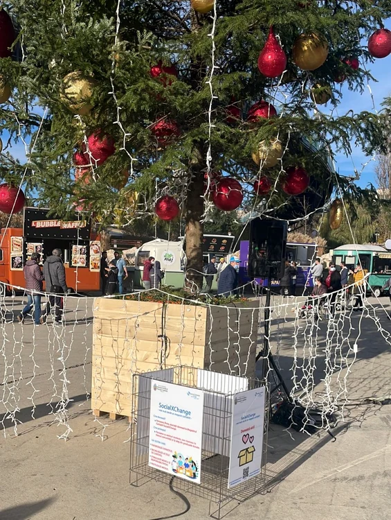 Coșul caritabil se află așezat sub bradul împodobit, la Târgul de Crăciun, din Parcul Drumul TabereiFotografii: Primăria Sectorului 6