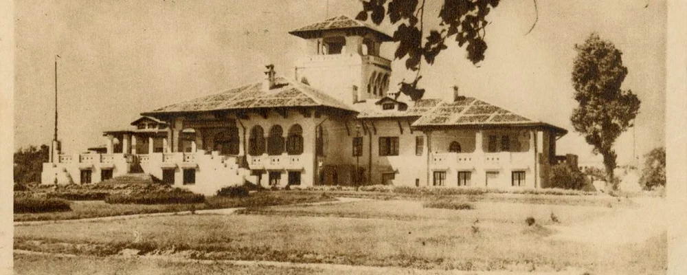 Vedere cu fosta vilă Regală de la Mamaia văzută dinspre mare. În imagine se poate vedea grădina din curtea vilei, intrarea cu scară și fațada estică a monumentului. Carte poștală din colecția Andrei Stomff