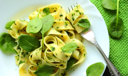 Tagliatelle pasta with spinach sauce and fresh leafs on a white plate jpeg
