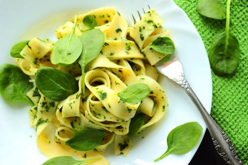 Tagliatelle pasta with spinach sauce and fresh leafs on a white plate jpeg