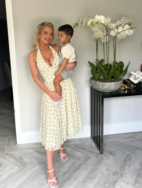 Helen Flanagan, într-o rochie albă și decoltată, cu fiul ei în brațe
