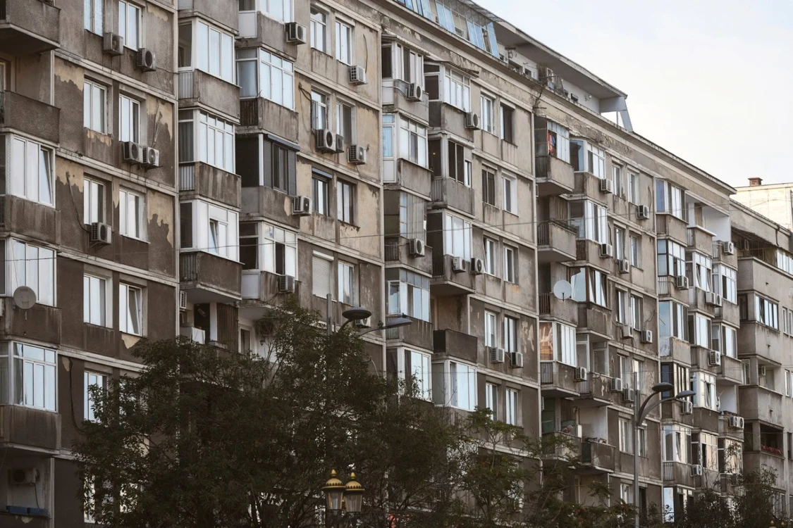 Doi tineri privesc blocuri de pe o terasă cu intenția de a alege zona unde vor locui