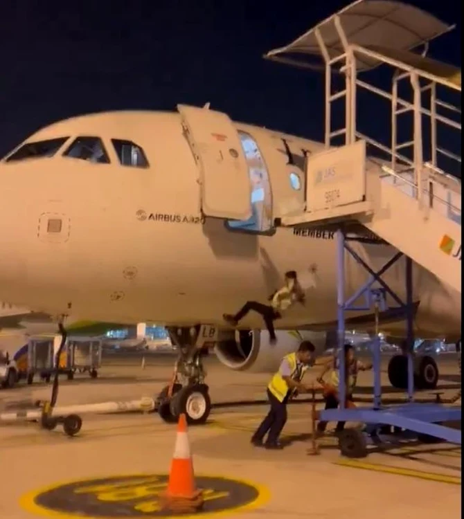 Momentul în care angajatul cade din avion, în timp ce colegii lui împig scara, captură video