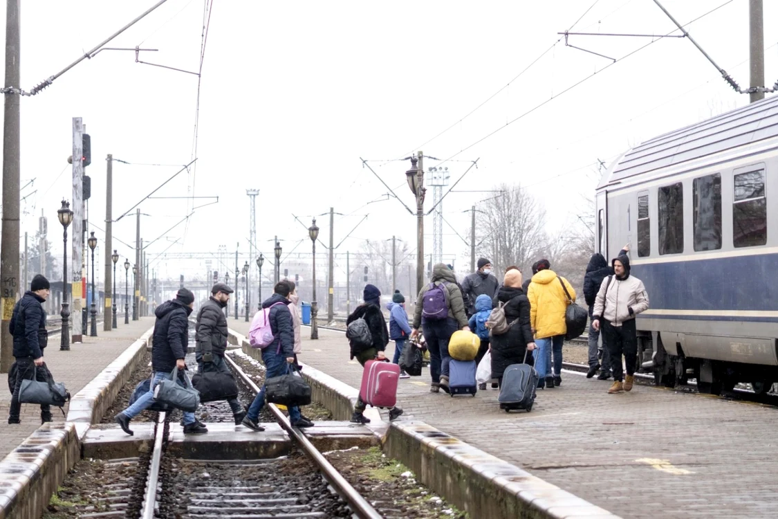 Refugiați ucraineni care își cară bagajele până la un tren