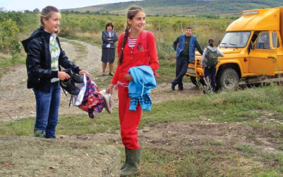 Ştefania Cucu (dreapta) îşi schimbă cizmele de cauciuc înainte de a ajunge la şcoală