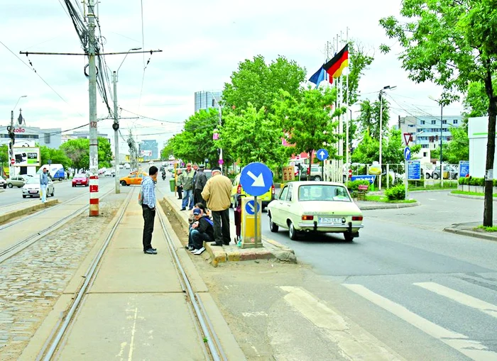 Fiindcă nu au loc pe refugiu, călătorii aşteaptă tramvaiul pe bordură