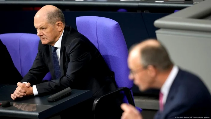 Cancelarul Olaf Scholz ascultând, vineri, discursul lui Friedrich Merz