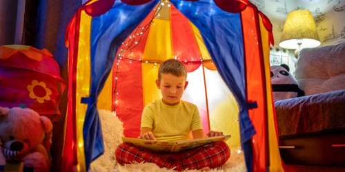 Copil băiat citește o carte în cort - spatiu privat - intimitate FOTO Shutterstock 