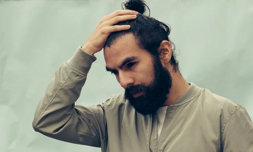 barbat brunet se tine cu mana de cap jpg