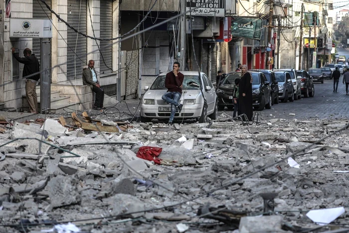 Mai mulţi palestinieni se uită la o clădire distrusă de un atac aerian al israelienilor în Palestina. FOTO EPA-EFE