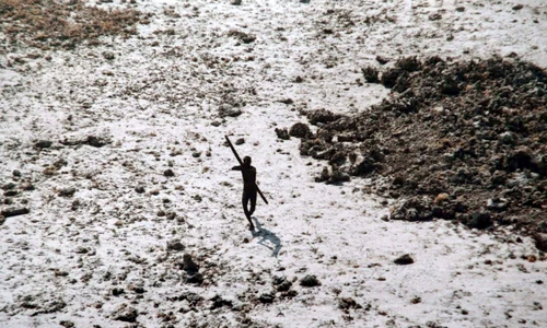 Imagine din 2004 cu un bărbat din tribul sentinelez își îndreaptă arcul și săgeata spre un elicopter al Gărzii de Coastă indiene FOTO AFP