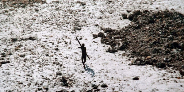 Imagine din 2004 cu un bărbat din tribul sentinelez își îndreaptă arcul și săgeata spre un elicopter al Gărzii de Coastă indiene FOTO AFP