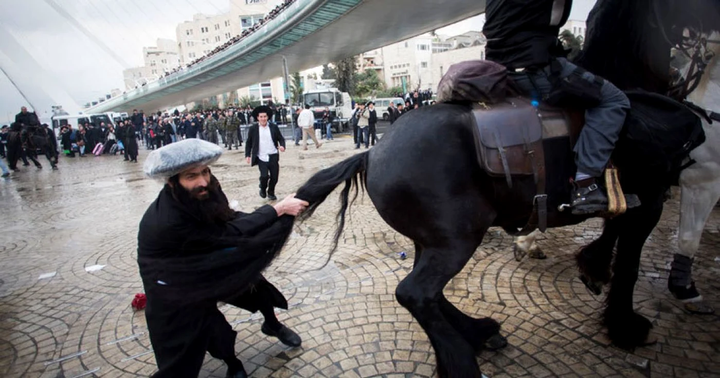 Un protestatar ultraortodox, atacând calul unuia dintr epoliţiştii israelieni. FOTO Reuters
