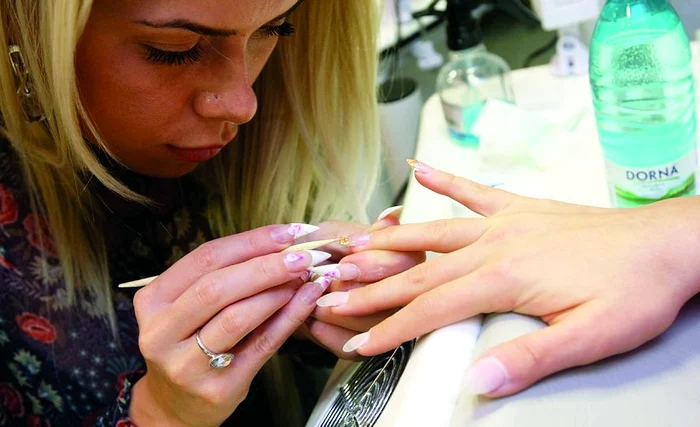 Aplicarea foiţei de aur se  realizează cu un beţişor  din lemn. Fiecare fâşie se  lipeşte pe unghie