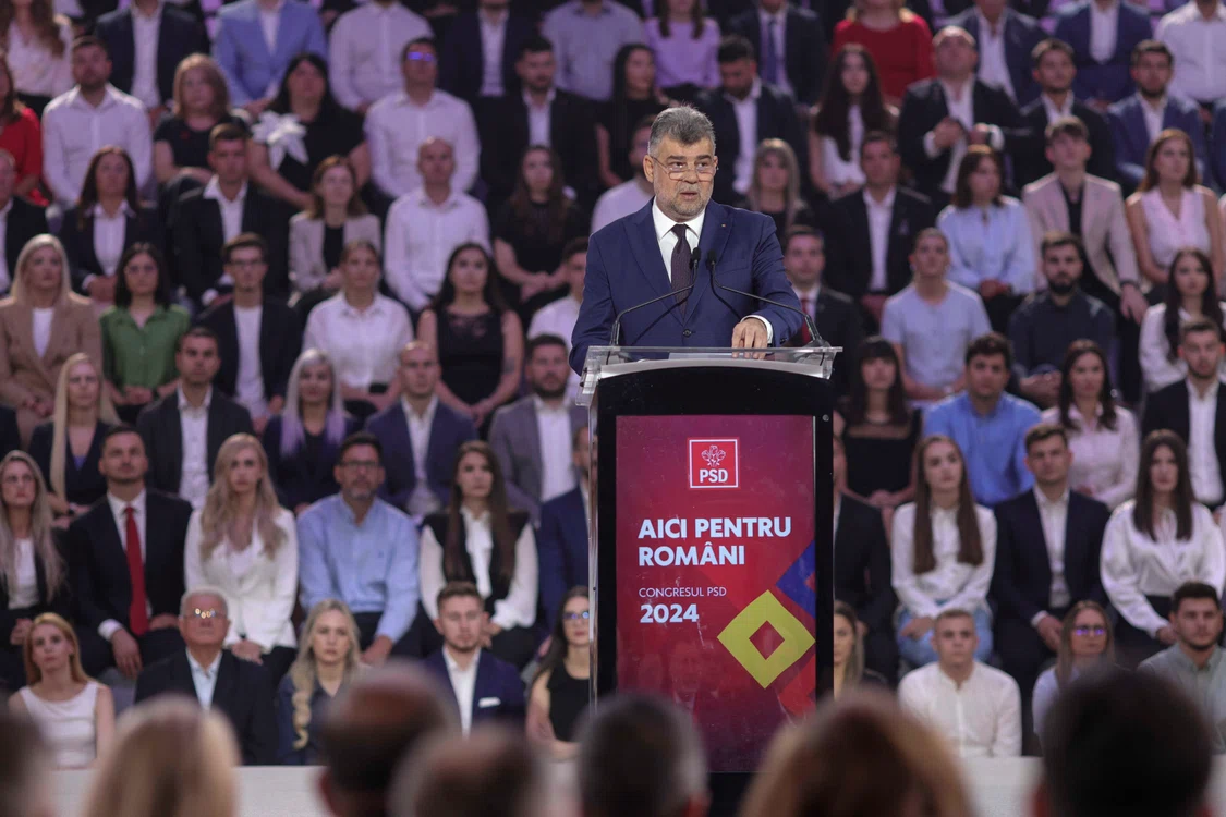 Marcel Ciolacu la pupitrul cu microfon la un eveniment marca PSD