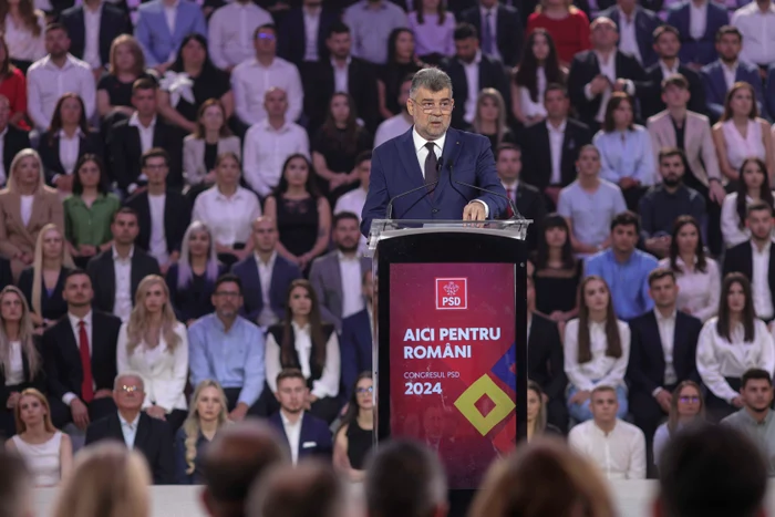 Marcel Ciolacu la pupitrul cu microfon la un eveniment marca PSD