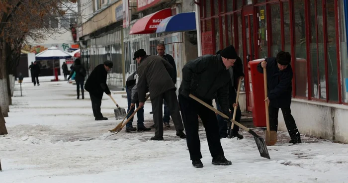 Oamenii muncesc de zor la îndepărtarea primului strat de gheaţă