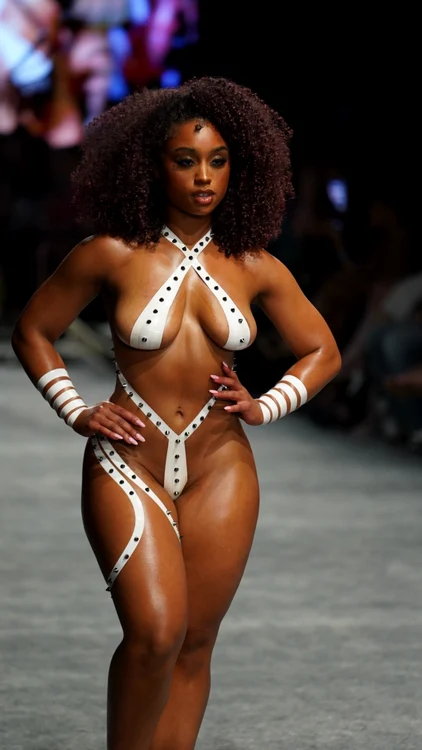 Un model imbrăcat într-un costum de baie din bandă adezivă albă, cu ținte