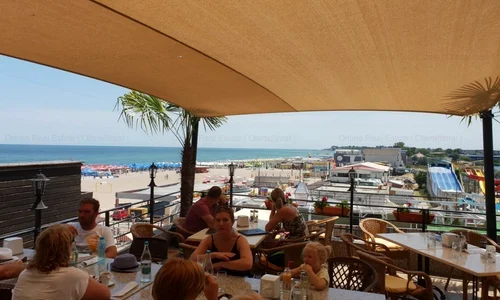 turisti la mare care iau masa la terasa jpeg