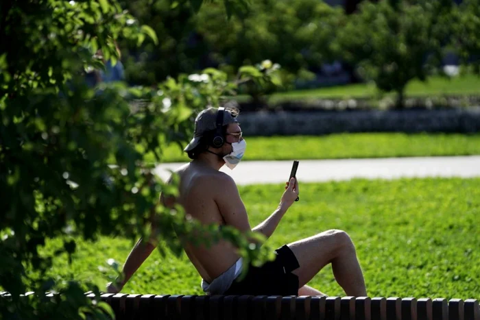 Un italian cu mască se relaxează într-un parc din Milano FOTO Getty Images