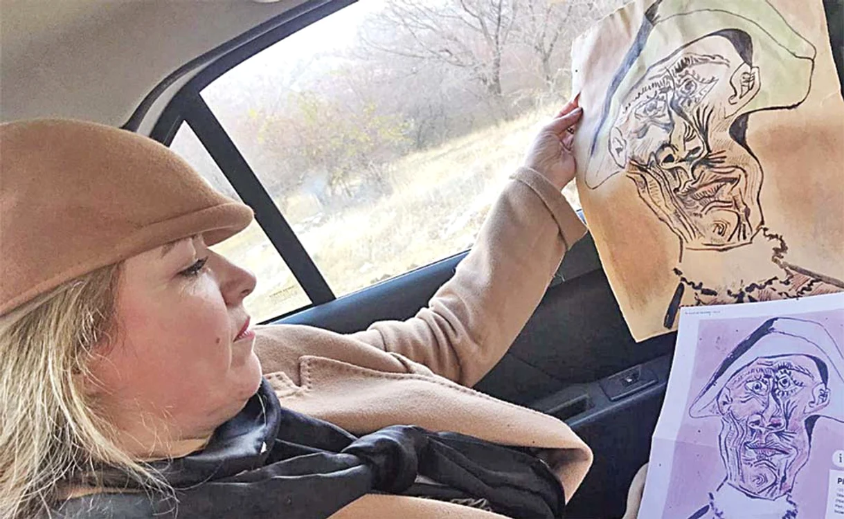 Mira Feticu, în maşină, comparând tabloul găsit cu o imagine din catalogFoto: Facebook / Mira Feticu