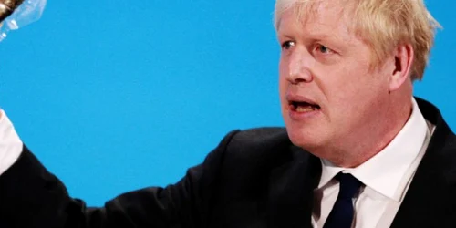 Boris Johnson ridică un peşte afumat pentru a demonstra o idee în timp ce vorbeşte la finalul campaniei pentru conducerea partidului Conservator la ExCeL Londra din Londra