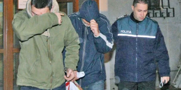 Cei doi poliţişti (cu feţele acoperite) au fost arestaţi pentru 29 de zile  