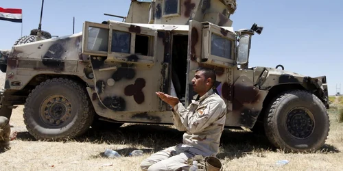 Un membru al armatei irakiene se roaga langa o masina la vest de Bagdad FOTO Reuters