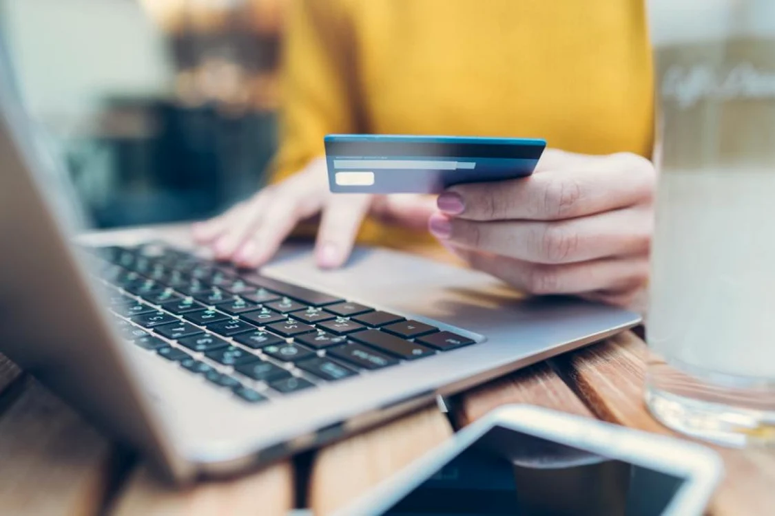 O tânără introduce datele cardului pentru cumpărăturile online