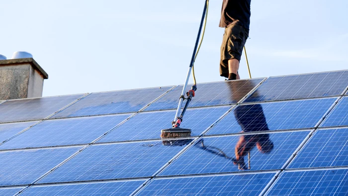 Cineva spală panourile fotovoltaice de pe un acoperiș