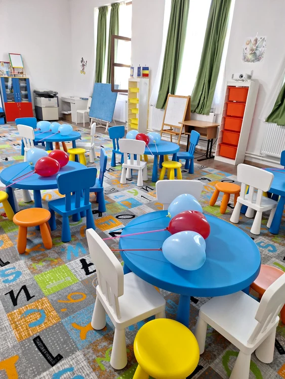 Interiorul unei grădinițe private cu scaune și mese colorate