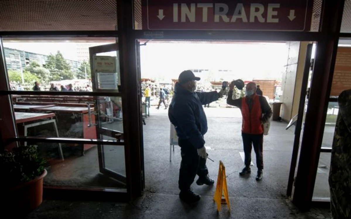 Un angajat al unei firme de securitate foloseşte un termoscaner pentru a lua temperatura celor care intră în Piaţa Obor din Bucureşti FOTO Inquam Photos / George Calin