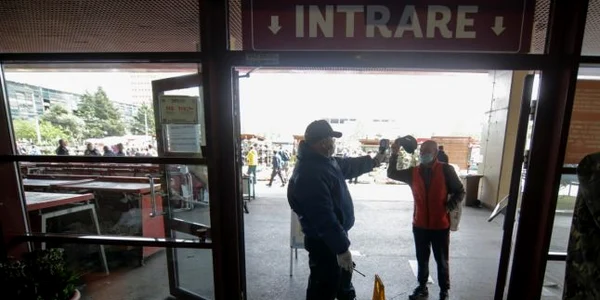 Un angajat al unei firme de securitate foloseste un termoscaner pentru a lua temperatura celor care intra in Piata Obor din Bucuresti Inquam Photos / George Calin