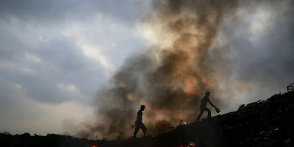 Indieni trec pe lângă gunoi arzând în suburbiile Mumbaiului India FOTO AP