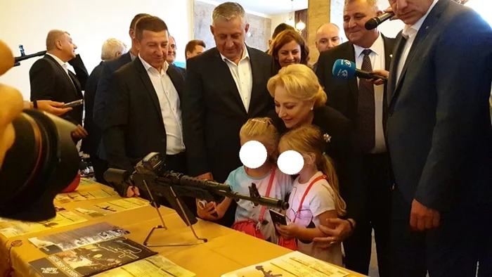 Dăncilă împreună cu două fetiţe admiră o puşcă de asalt produsă la Fabrica de Arme. Foto: alba24.ro