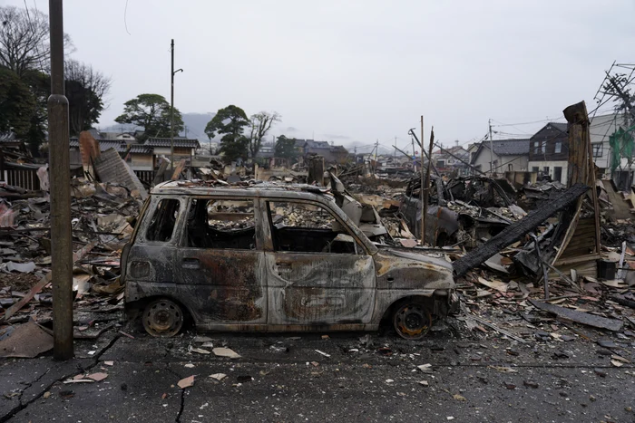 stradă cu o mașină carbonizată și dărîmături în urma cutremururlui din Japonia 