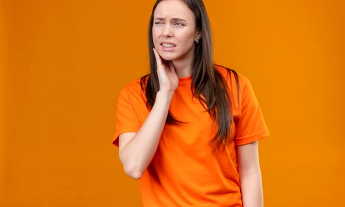 young beautiful girl wearing orange t shirt looking unwell touching her cheek feeling toothache standing isolated orange background jpg