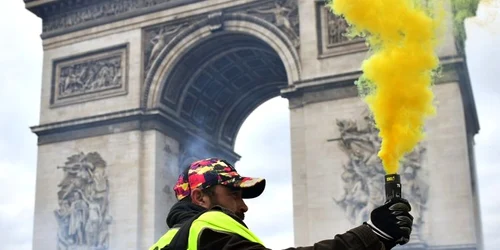 Un protestatar de la Gilets Jaunes (Veste galbene) aprinde o fumigenă în apropiere de Champs Elysees în timpul demonstraţiei Act XVIII la Paris Franţa FOTO EPA-EFE / Julien De Rosa