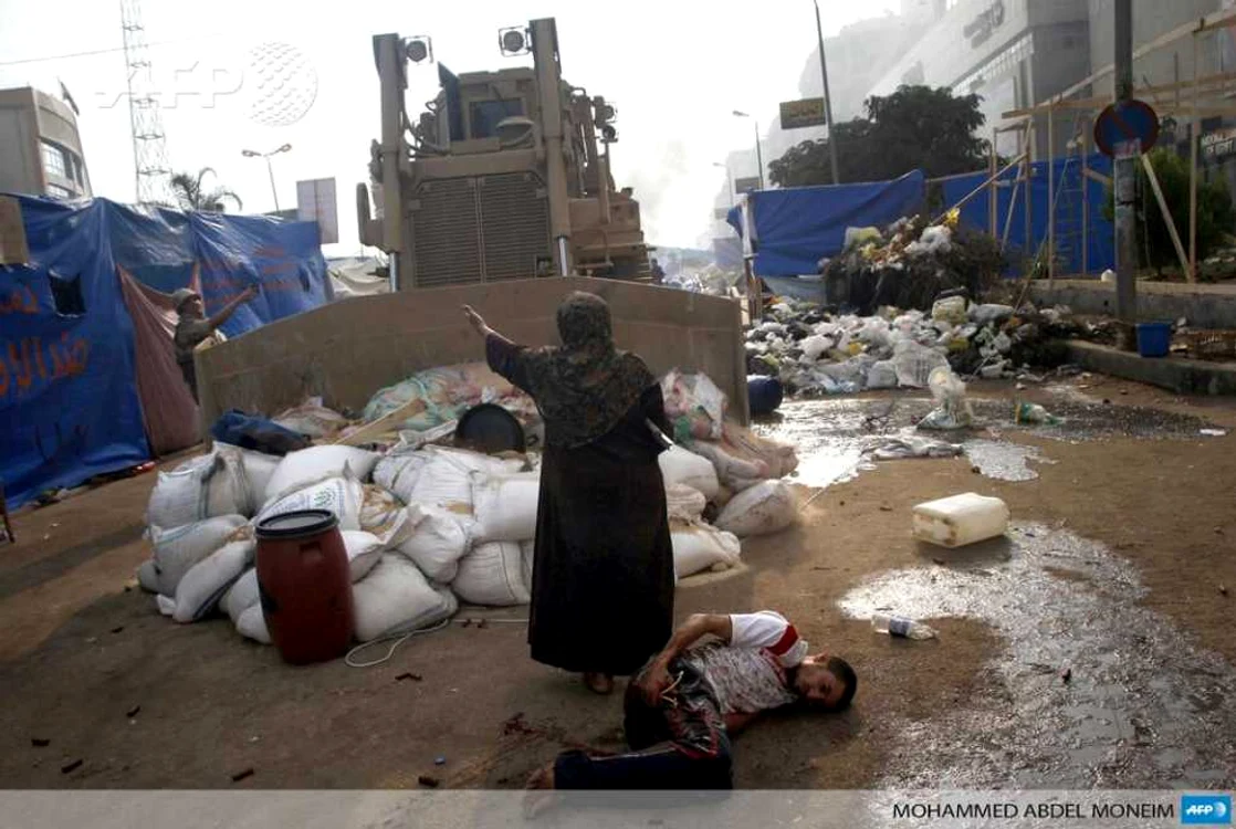 O femeie încearcă să oprească buldozerele să treacă pentru trupul unui rănit. FOTO: Reuters