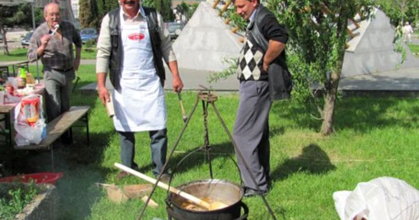 Un cioban pregăteşte oaie cu smântână la ceaun în faţa turiştilor.