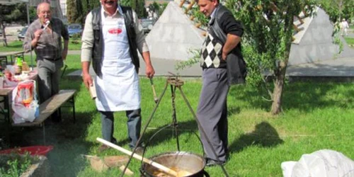 Un cioban pregăteşte oaie cu smântână la ceaun în faţa turiştilor.