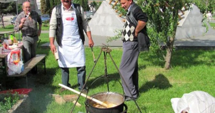 Un cioban pregăteşte oaie cu smântână la ceaun în faţa turiştilor.