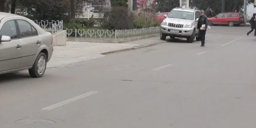 Pietonii sunt nevoiţi să ocolească pe stradă maşinile parcate pe trotuar FOTO