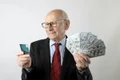 un barbat cu ochelari tine in mana drapta un card de credit si in mana stanga bancnote dolari jpg