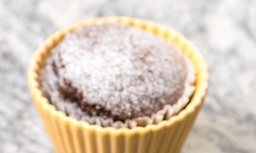 Chocolate cup cakes with powdered sugar in the porcelain bowls above grey granite background jpeg