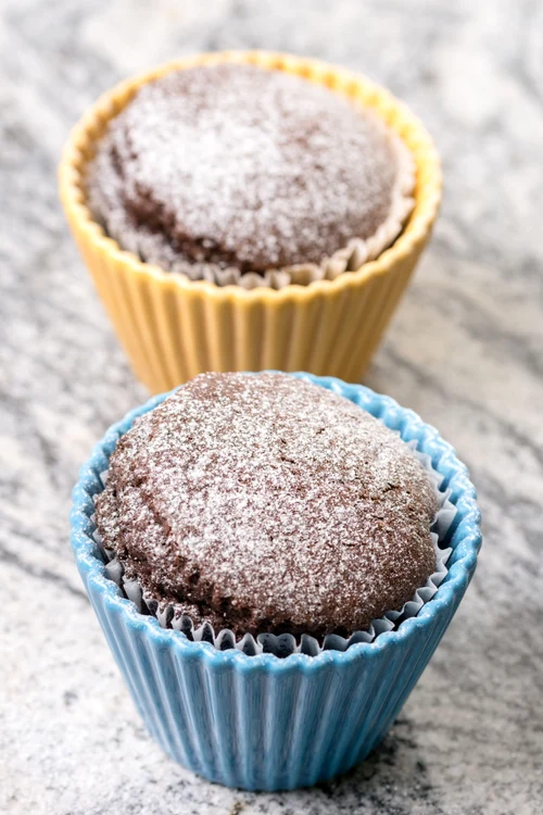 Chocolate cup cakes with powdered sugar in the porcelain bowls above grey granite background jpeg