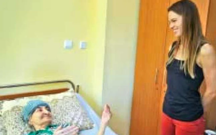 Hilary schimbă câteva cuvinte cu o bătrână internată la centrul pentru bătrâni „Floare Roşie“