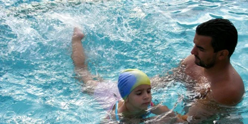 O fetiţă este deprinsă cu apa de un instructor profesionist